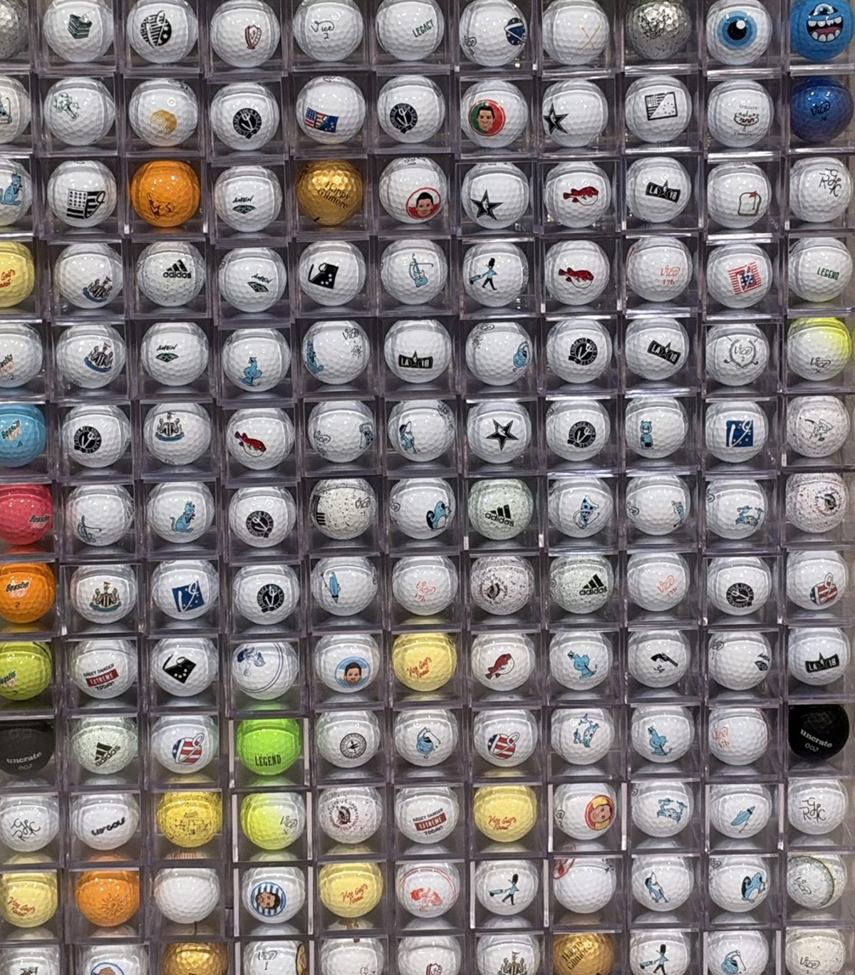 A wall of golf balls, each in its own clear display cube